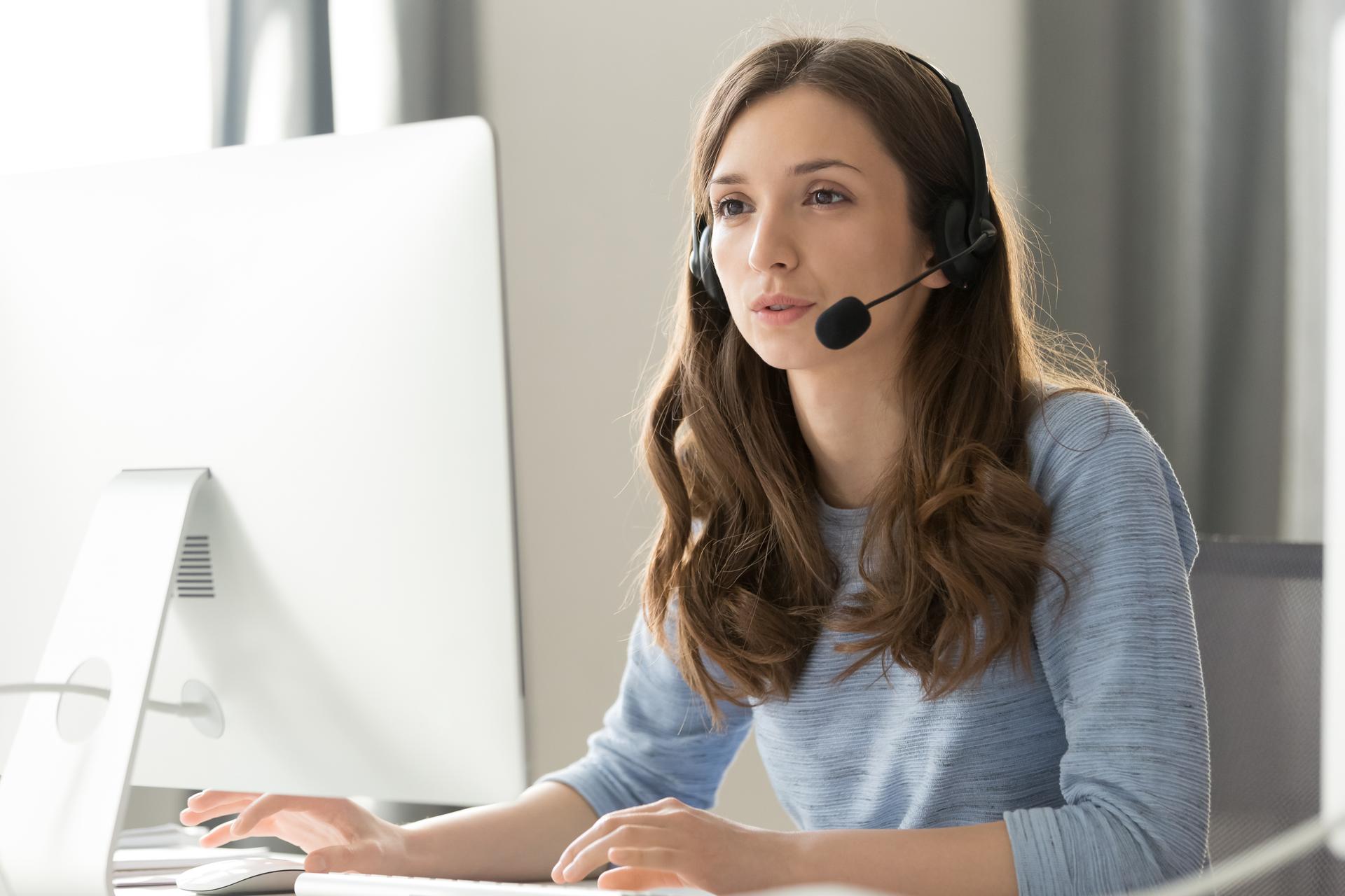 Femme d'affaires dans l'agent de centre d'appel de casque consultant la conférence vidéo participante